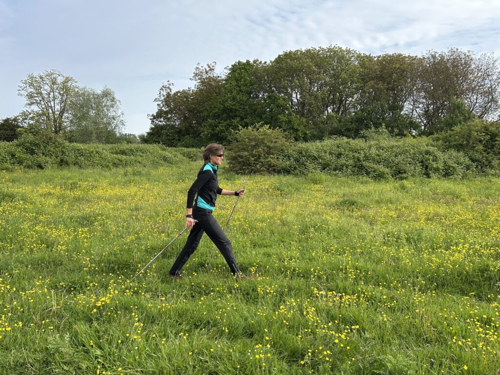 Vrouw doet aan nordic Walking in een grasveld